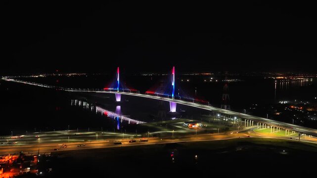 Aerial night shot of Heroes of Chaco Bridge over the Paraguay River, lit up in red, white, and blue