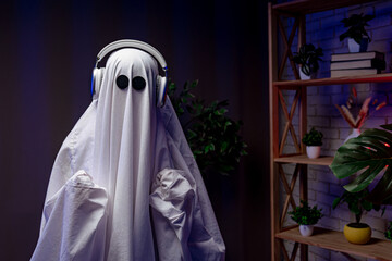A funny Halloween ghost in a white sheet with black eyes in a dark room with neon lights, dancing...