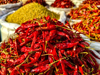 A variety of spices, including red chili peppers, are displayed at a market in Asia.