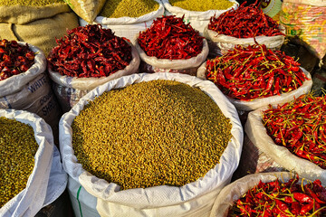 A variety of spices, including red chili peppers, are displayed at a market in Asia.