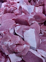 Close-up of raw pork cuts piled together, showing pink-red meat, fat layers, and marbling.