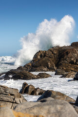 Big Ocean Wave Crashing Against Rock with Dramatic Splash Showing Power of the Sea under Clear Blue...