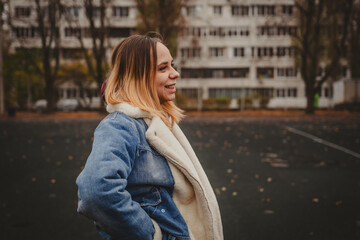 A young woman explores an urban park during an overcast day, surrounded by towering buildings and...