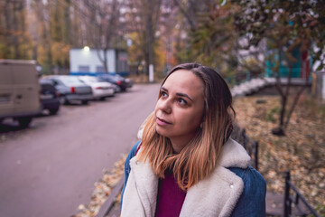 A young woman gazes thoughtfully upwards on a serene autumn day in a peaceful urban park setting...