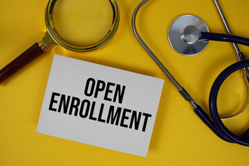 Open Enrollment text on paper card with Stethoscope flat lay on yellow background
