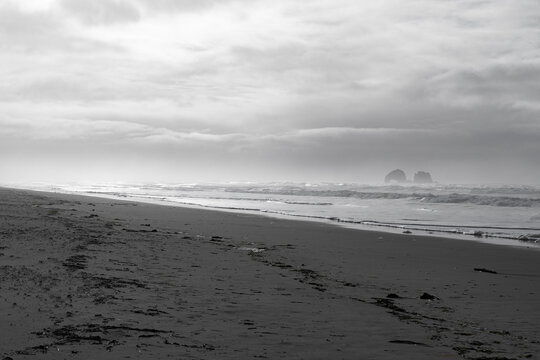 Oregon coastline on a stormy winter day, deserted shore with rock formations in the distance, horizontal aspect