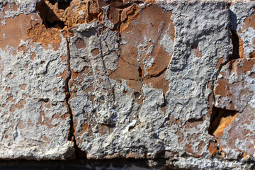 Close-up view of weathered and peeling paint on a textured surface, showcasing layers of rust and...