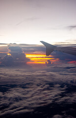 Fototapeta premium Scenic aerial view from an airplane wing capturing a vibrant sunset over the clouds, showcasing the beauty of travel and nature.