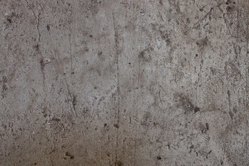 A close-up view of a textured concrete surface showcasing various imperfections and stains,...