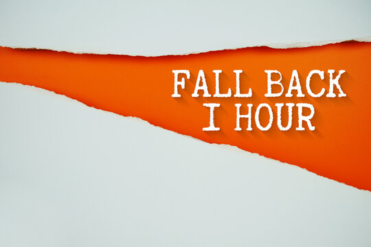 Fall Back 1 Hour text on orange with white paper torn ripped of horizontal