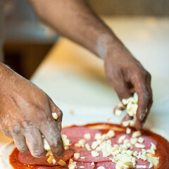 Hands preparing a pizza putting cheese mozzarella on pizza