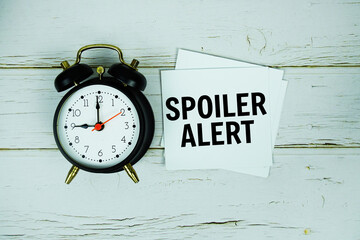 Spoiler Alert text wiht alarm clock on wooden background