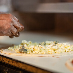 Hands preparing a pizza putting cheese mozzarella on pizza