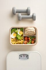 A vertical balanced meal with vegetables, grains, and protein, beside dumbbells and a weight scale