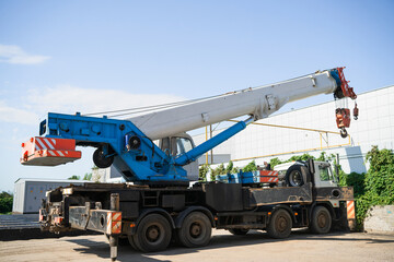 A white and blue truck crane at a construction site is preparing for loading