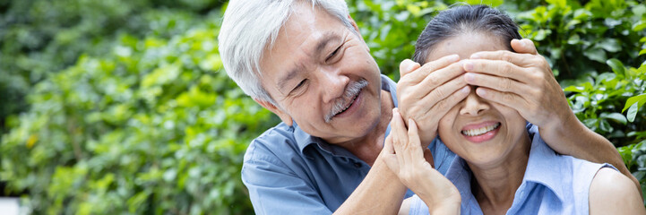 Playful Asian senior couple, old man close his wife eyes and let her guess who is he, concept of...
