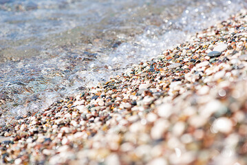 Sea colored pebbles on the beach, clear sea water