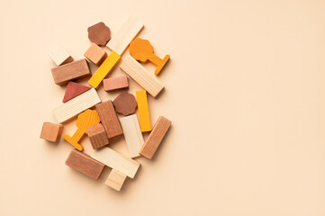 Wooden children's construction set blocks of different shapes natural colors on beige background. Montessori style cubes game for toddlers flat lay top view. Concept of learning and education