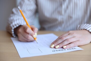 Student filling out multiple choice test at table, closeup. Passing exam