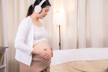 Asian pregnant woman listening music with headphones, hand on belly, relaxing with maternity lifestyle, bonding, wellness, happiness, emotion and prenatal care, relaxing time, giving birth expectation