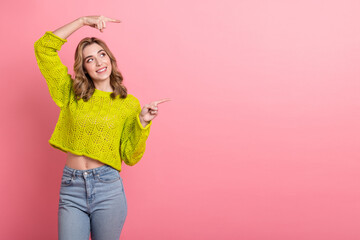Cheerful young woman in stylish yellow knitwear posing cheerfully against a pink background in a...