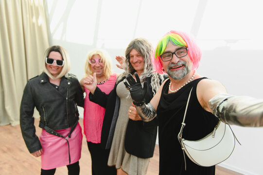 Drag queens taking a selfie wearing colorful wigs and makeup