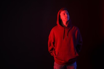 Handsome man in neon lights against black background. Space for text