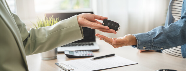 Agent in auto leasing giving key of car to client after all document and paperwork contract signed.