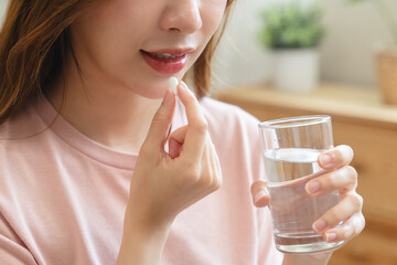 Healthcare Harmony: Close-Up Hands Holding Medication and Water Glass for Optimal Wellness,...