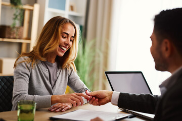Happy woman receiving keys from financial advisor during loan approval meeting
