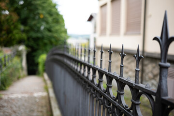 Wrought iron fence with sharp, pointy ends. Side view, shallow depth of field, no people.