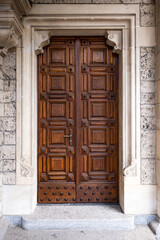 Large, ornate, closed, wooden church entry door in a European city, no people