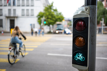 Bicycle traffic light next to pedestrian crossing, showing green. Close up, wide angle shot, shallow depth of field, blurry cyclist in the background