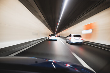 Blurry cars driving through a tunnel in Europe. Long exposure, artificial illumination, through the windshield point of view, no people