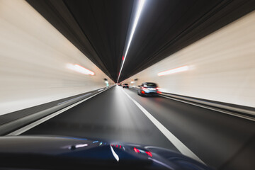 Blurry cars driving through a tunnel in Europe. Long exposure, artificial illumination, through the windshield point of view, no people