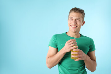 Man with juice and drinking straw on light blue background, space for text