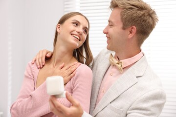 Marriage proposal. Smiling man with engagement ring and his happy girlfriend at home
