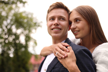 Marriage proposal. Woman with engagement ring hugging her smiling fiance outdoors, low angle view. Space for text