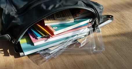 Holding steady camera on unzipped shoulder bag at wooden table, showcasing colorful notebooks - Powered by Adobe