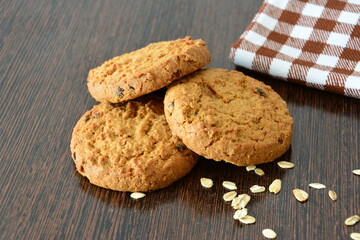 Delicious oatmeal cookies on a wooden table with oats and a checkered cloth
