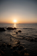 Sunset view over the calm sea with gentle waves reflecting the warm orange and purple hues of the evening sky. A peaceful and tranquil seascape symbolizing relaxation and the beauty of nature.