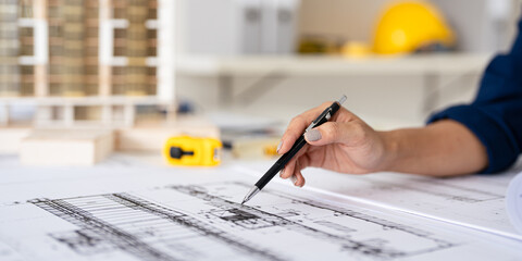 Close up hand of Architect or engineer hand holding pen working on blueprint construction floor...