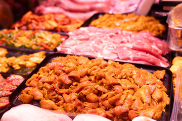 Meat department of store sells chicken meat marinated with addition of curry seasoning.