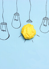 creative concept idea. Painted light bulb with a crumpled paper yellow ball.. Vertical photo format