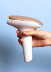 Fototapeta premium Modern home photoepilator in female hands. Remove unwanted hair.. Vertical photo format