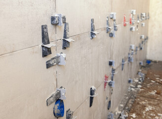 Flat wall tile leveling system. Process of installation of tiles in the bathroom. Home improvement