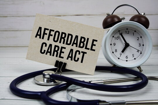 Affordable Care Act text message on paper card with stethoscope and alarm clock on wooden background