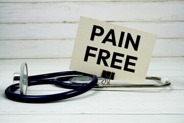 Pain Free text message on paper card with stethoscope on wooden background