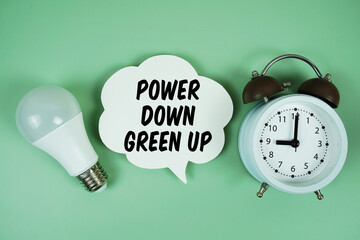 Power Down, Green Up with light bulb and alarm clock on green background