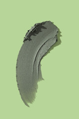 Smear of a gray magnetic or charcoal mask on mint green isolated background. Smudge texture brush stroke. Beauty product sample swatch
